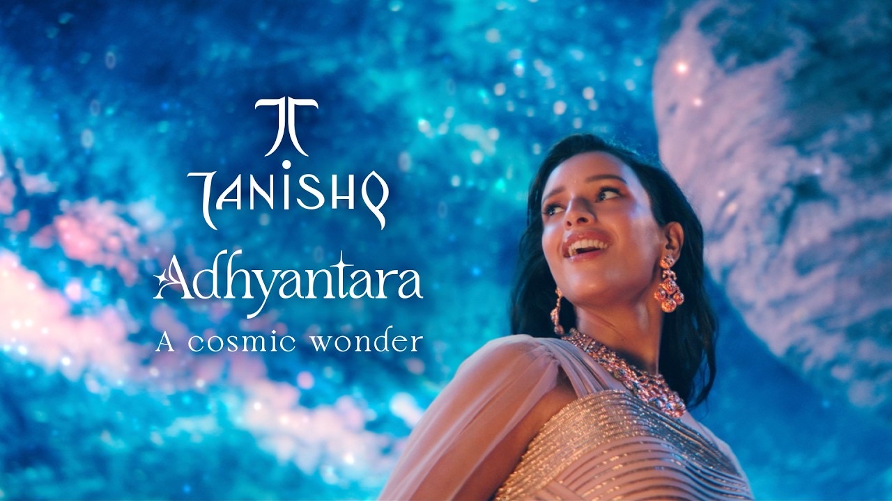 Triptii Dimri in a pale embellished outfit and drop earrings looks up at a starry blue sky beside the Tanishq Adhyantara, a cosmic wonder, title