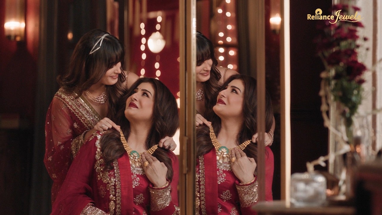 Raveena Tandon in a red outfit has a gold necklace fastened by Rasha Thadani, reflected in a dressing mirror, Reliance Jewels Diwali 2026